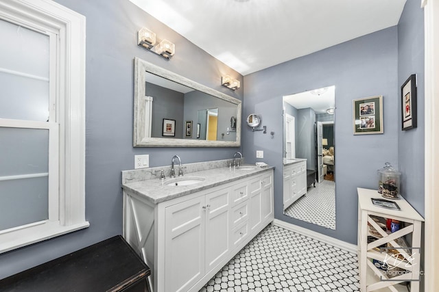 full bath with double vanity, baseboards, and a sink