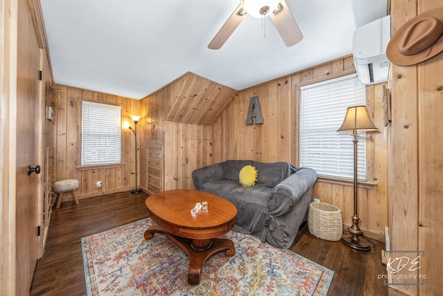 living area with a ceiling fan, wooden walls, and wood finished floors