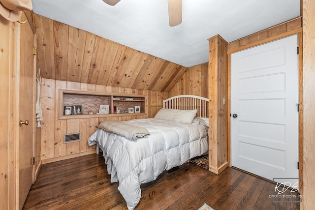 bedroom featuring lofted ceiling, dark wood-type flooring, wood walls, and visible vents