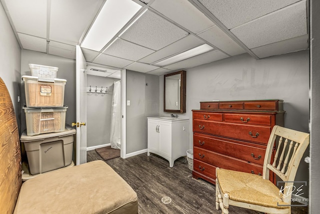 basement with visible vents, baseboards, a drop ceiling, dark wood-type flooring, and a sink