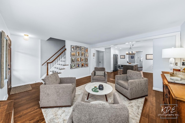 living room with stairs, dark wood-style flooring, and baseboards