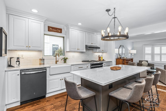 kitchen with dark wood-style floors, stainless steel appliances, a breakfast bar, and a sink