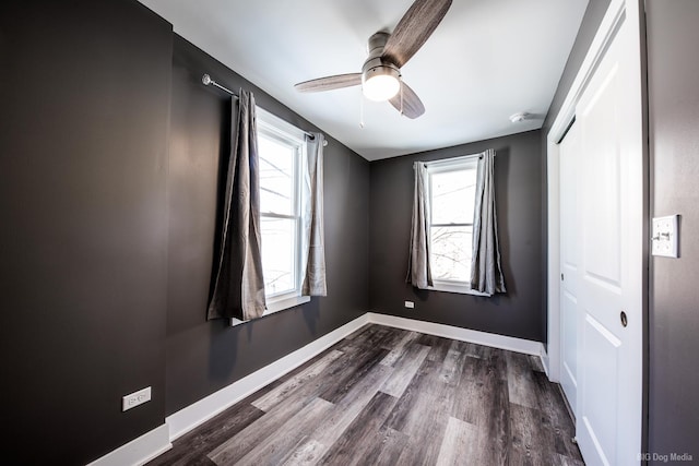 empty room with baseboards, ceiling fan, dark wood-style flooring, and a healthy amount of sunlight