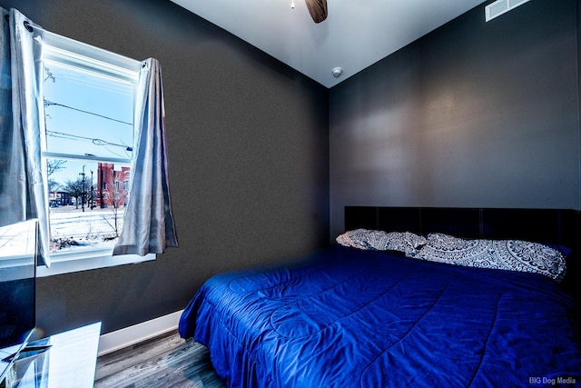 bedroom with ceiling fan, wood finished floors, visible vents, and baseboards