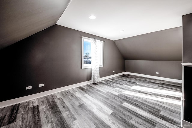 additional living space with baseboards, vaulted ceiling, and wood finished floors