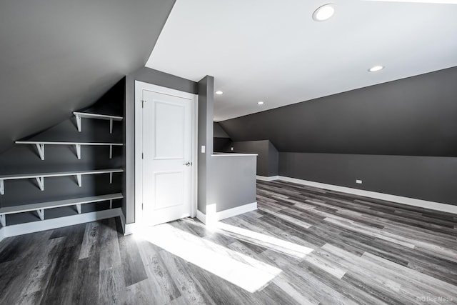 additional living space with vaulted ceiling, wood finished floors, and baseboards