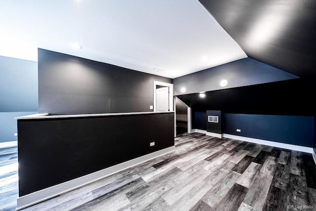 cinema room featuring lofted ceiling, visible vents, baseboards, and wood finished floors