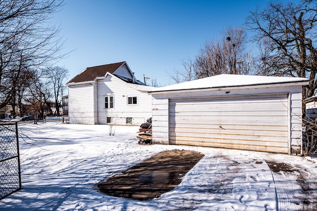 snow covered property with a garage and an outdoor structure