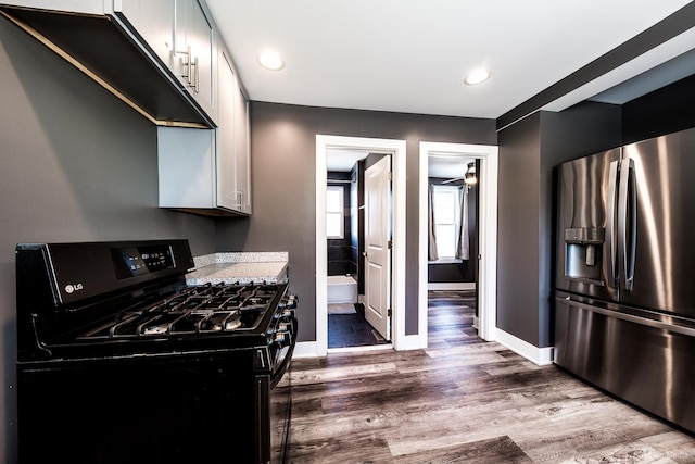 kitchen with recessed lighting, black range with gas cooktop, wood finished floors, stainless steel fridge, and baseboards