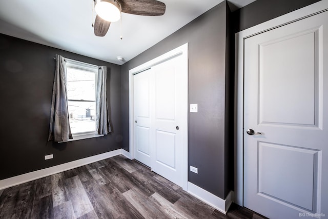 unfurnished bedroom featuring dark wood-type flooring, a closet, a ceiling fan, and baseboards