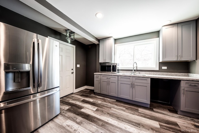 kitchen with baseboards, dark wood-style floors, appliances with stainless steel finishes, gray cabinetry, and a sink