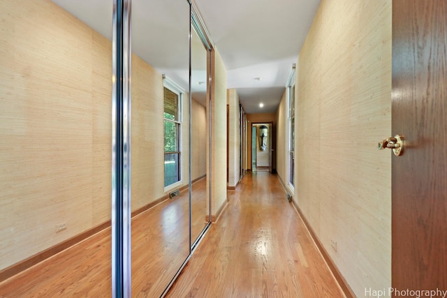 hallway featuring baseboards, visible vents, and light wood-style floors