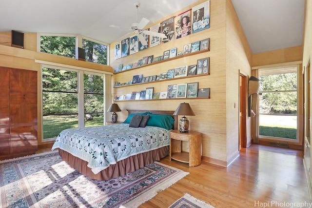 bedroom featuring high vaulted ceiling, wood finished floors, visible vents, and baseboards