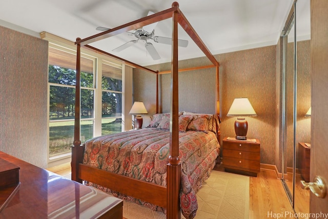 bedroom featuring ceiling fan, wallpapered walls, and light wood-style floors