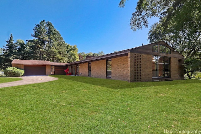 view of front of house featuring a garage, driveway, a front lawn, and brick siding