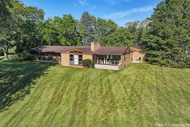 view of front of house with brick siding, a chimney, and a front yard