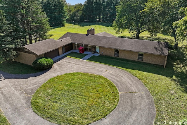 view of front of property featuring aphalt driveway, a front yard, brick siding, and a chimney