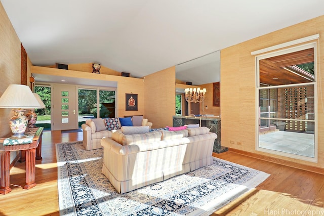 living room with a chandelier, lofted ceiling, and wood finished floors