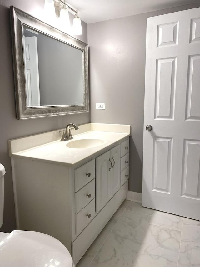 half bath with marble finish floor, vanity, toilet, and baseboards