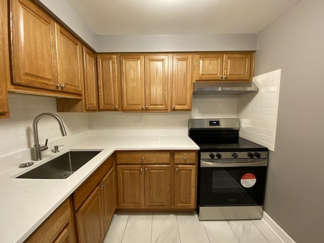 kitchen with stainless steel range with electric stovetop, under cabinet range hood, brown cabinets, and a sink