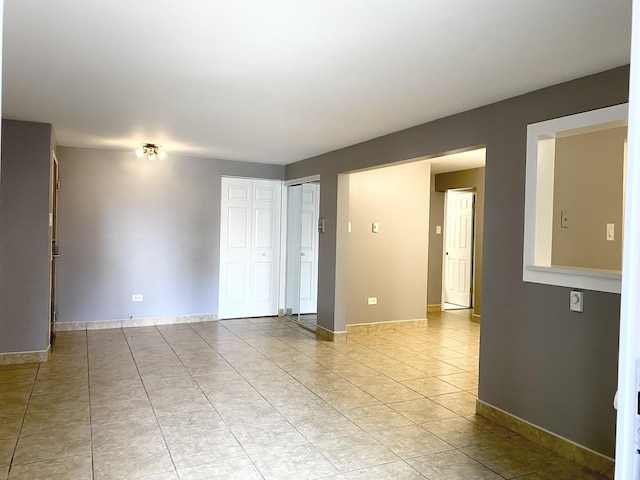 empty room with light tile patterned flooring and baseboards