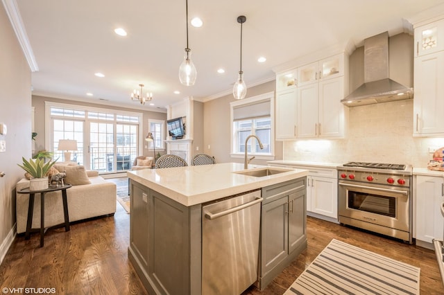 kitchen featuring dark wood-type flooring, wall chimney exhaust hood, appliances with stainless steel finishes, and a sink