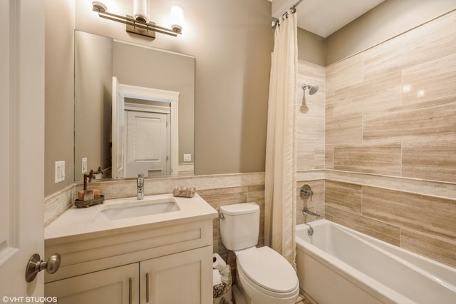 full bathroom with vanity, a wainscoted wall, tile walls, toilet, and shower / tub combo with curtain