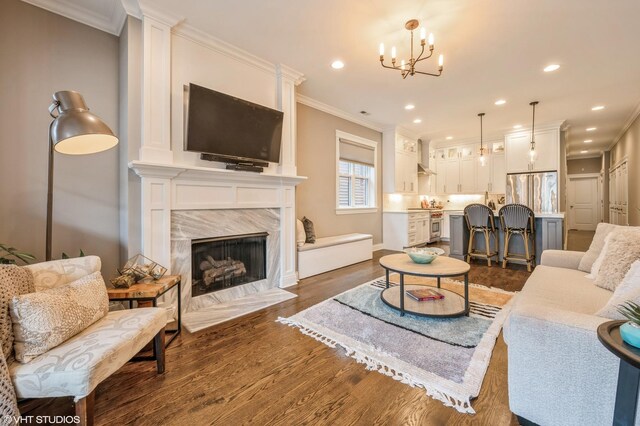 living area with recessed lighting, a fireplace, ornamental molding, dark wood-type flooring, and a notable chandelier