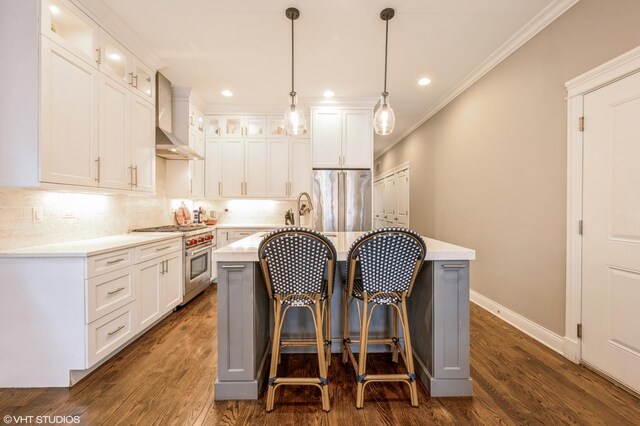 kitchen featuring ornamental molding, premium appliances, wall chimney range hood, dark wood-style floors, and light countertops