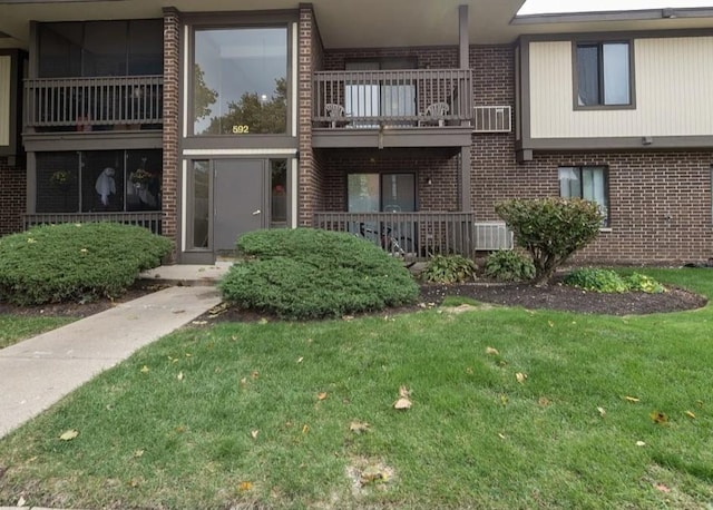 exterior space with a balcony, a front lawn, and brick siding