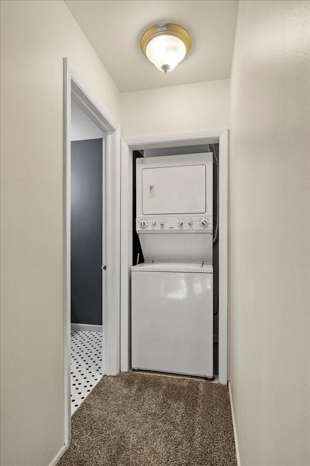 clothes washing area with stacked washer and dryer, carpet, laundry area, and baseboards