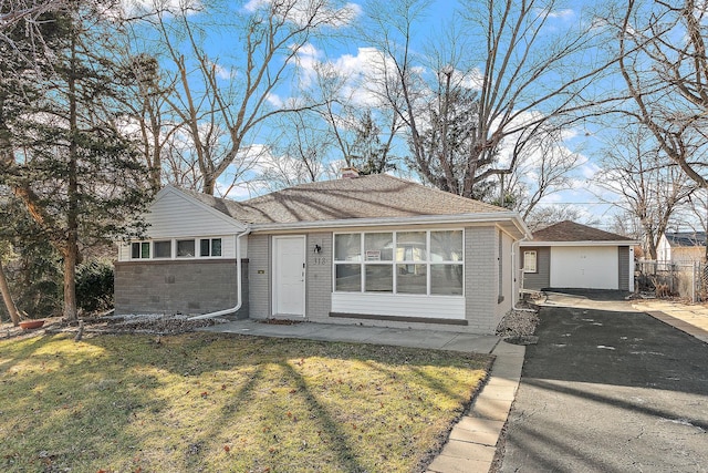 ranch-style home featuring aphalt driveway, a chimney, a front lawn, and brick siding