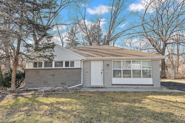 ranch-style house with a front yard, a chimney, fence, and brick siding