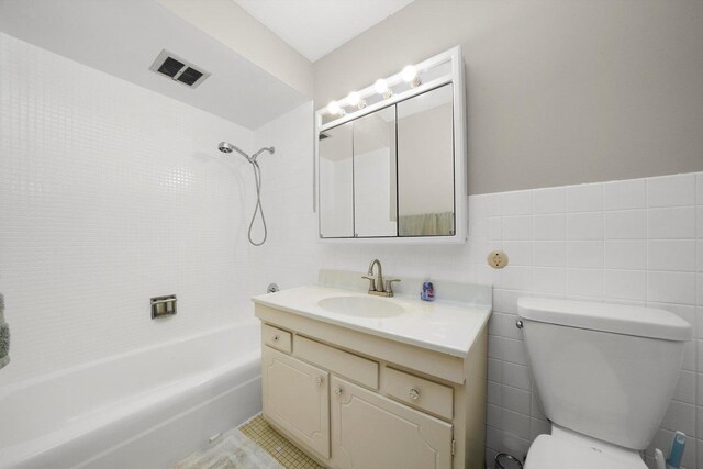 full bathroom with toilet, vanity, visible vents, tile walls, and tub / shower combination