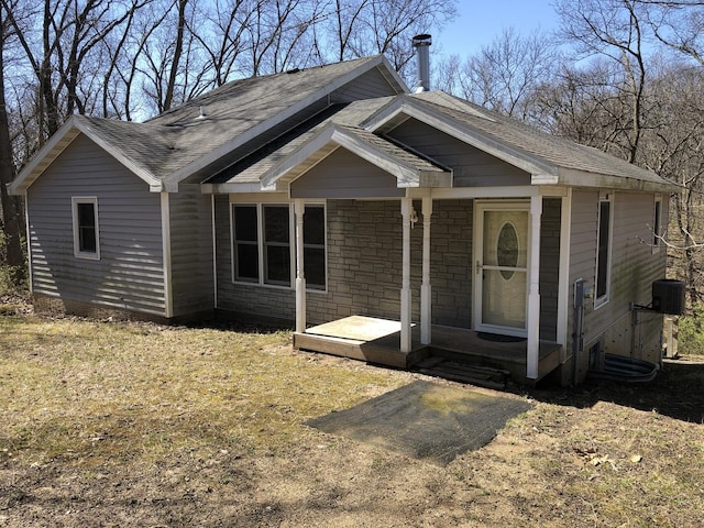 view of front of home featuring central air condition unit, stone siding, and roof with shingles