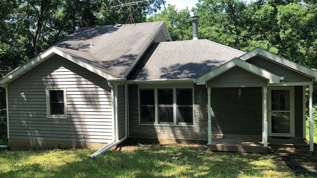 exterior space featuring stone siding, a shingled roof, and a front yard