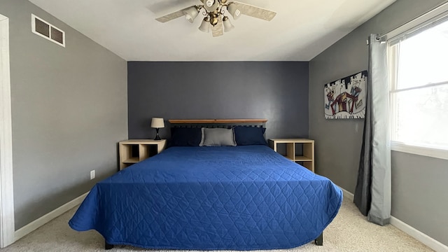 carpeted bedroom featuring baseboards, visible vents, and a ceiling fan