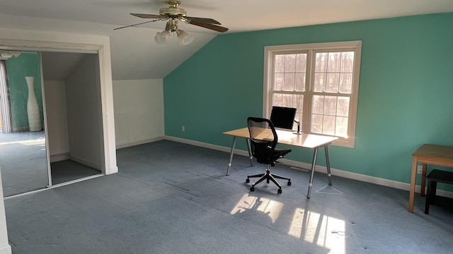 unfurnished office with vaulted ceiling, carpet flooring, a ceiling fan, and baseboards