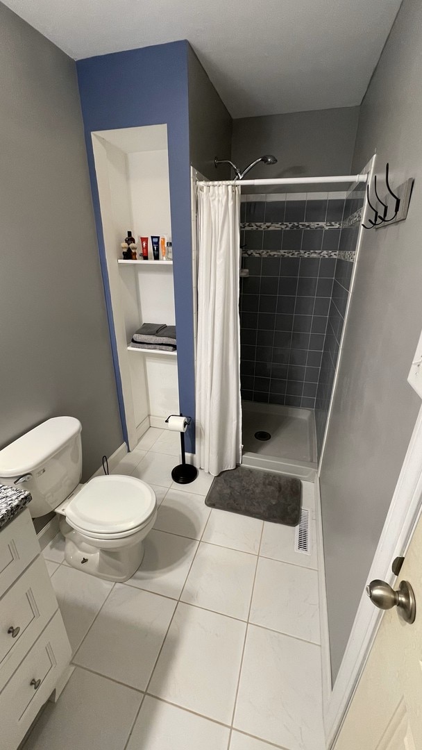 bathroom with a stall shower, vanity, and toilet