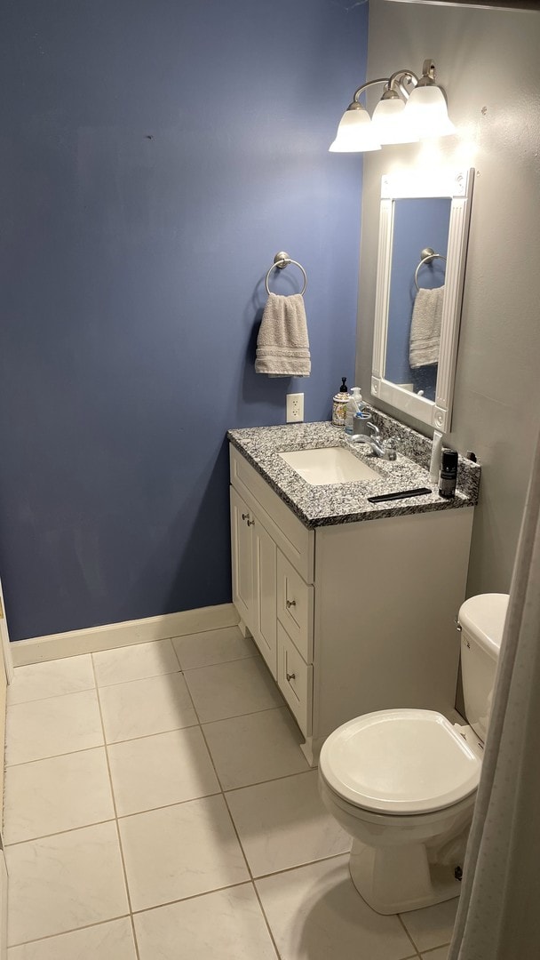 bathroom with toilet, tile patterned flooring, baseboards, and vanity