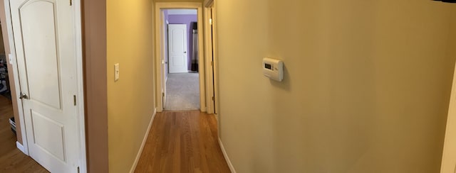 corridor with baseboards and wood finished floors