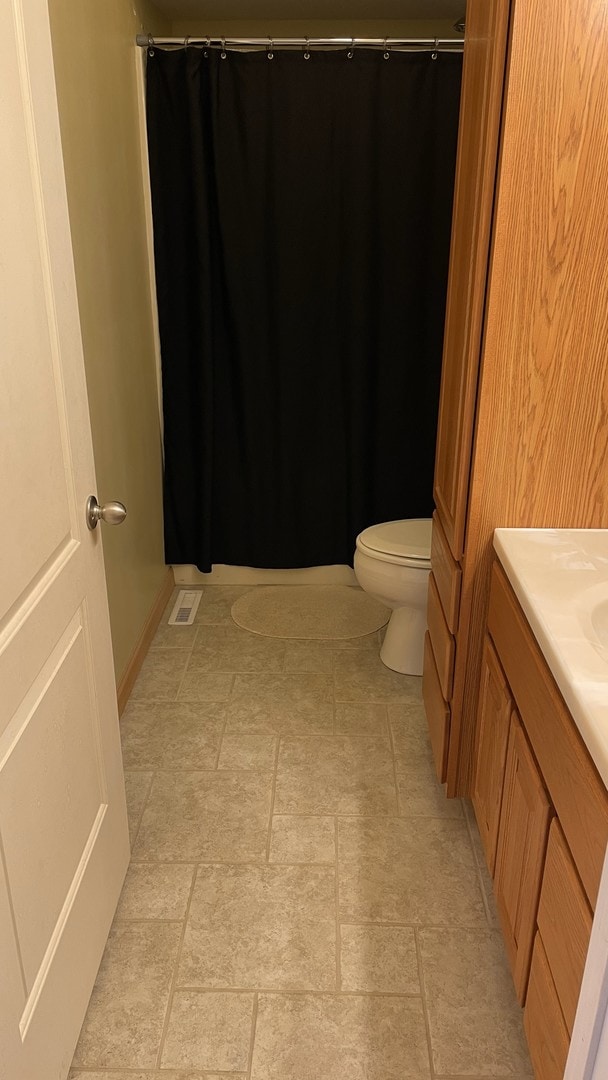 bathroom with curtained shower, visible vents, vanity, and toilet