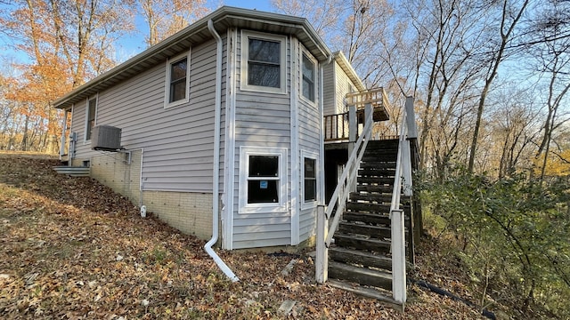 view of property exterior featuring central air condition unit, stairway, and brick siding