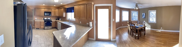 kitchen featuring stainless steel range with gas cooktop, light countertops, freestanding refrigerator, white dishwasher, and black microwave