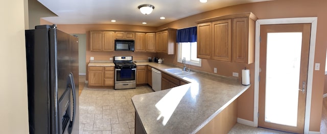 kitchen with recessed lighting, a peninsula, a sink, light countertops, and black appliances