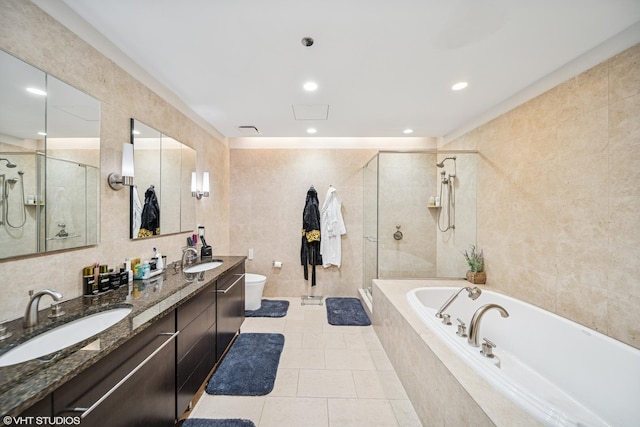 full bathroom featuring tile walls, toilet, a bath, a shower stall, and a sink