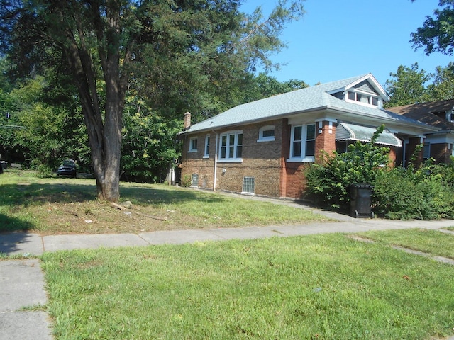 view of side of property featuring a lawn and brick siding