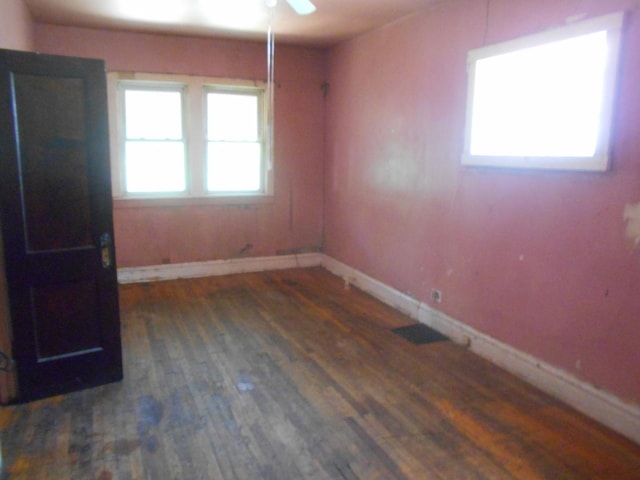 unfurnished room featuring a ceiling fan, visible vents, baseboards, and wood finished floors