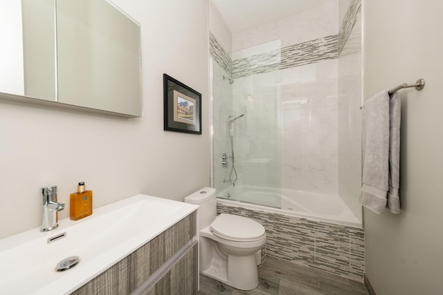 bathroom with toilet, tiled shower / bath, wood finished floors, and vanity