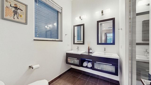 bathroom featuring baseboards, a sink, toilet, and tile patterned floors